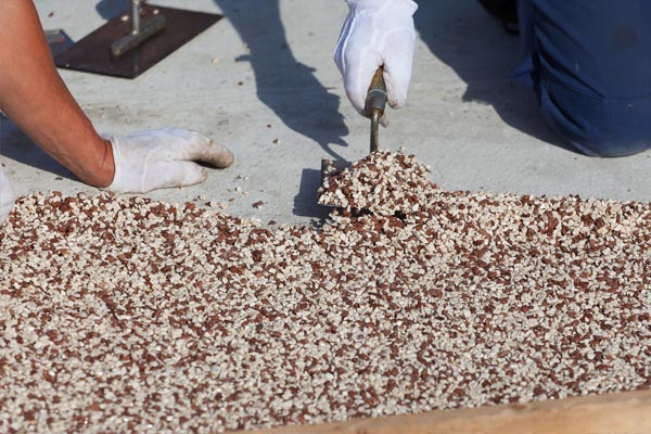 This image shows 2 men putting pebbles on concrete that is being resurfaced.