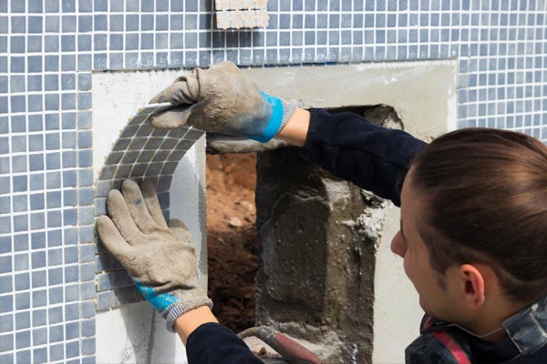 This shows an image of a man putting pool tiles.